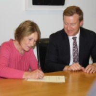 Kristine Bartlett signs the terms of the offer with Health Minister Jonathan Coleman